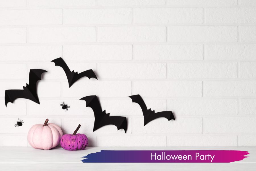 Schwarze Fledermäuse und Spinnen als Halloween-Deko vor weißer Wand mit pinken Kürbissen – perfekt für die Party in der Tanzschule Regensburg.