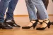 Tanzpaare beim gemeinsamen Tanzkurs auf einem Parkettboden in der Tanzwelt Regensburg – elegante Tanzschuhe und dynamische Schritte im Vordergrund.